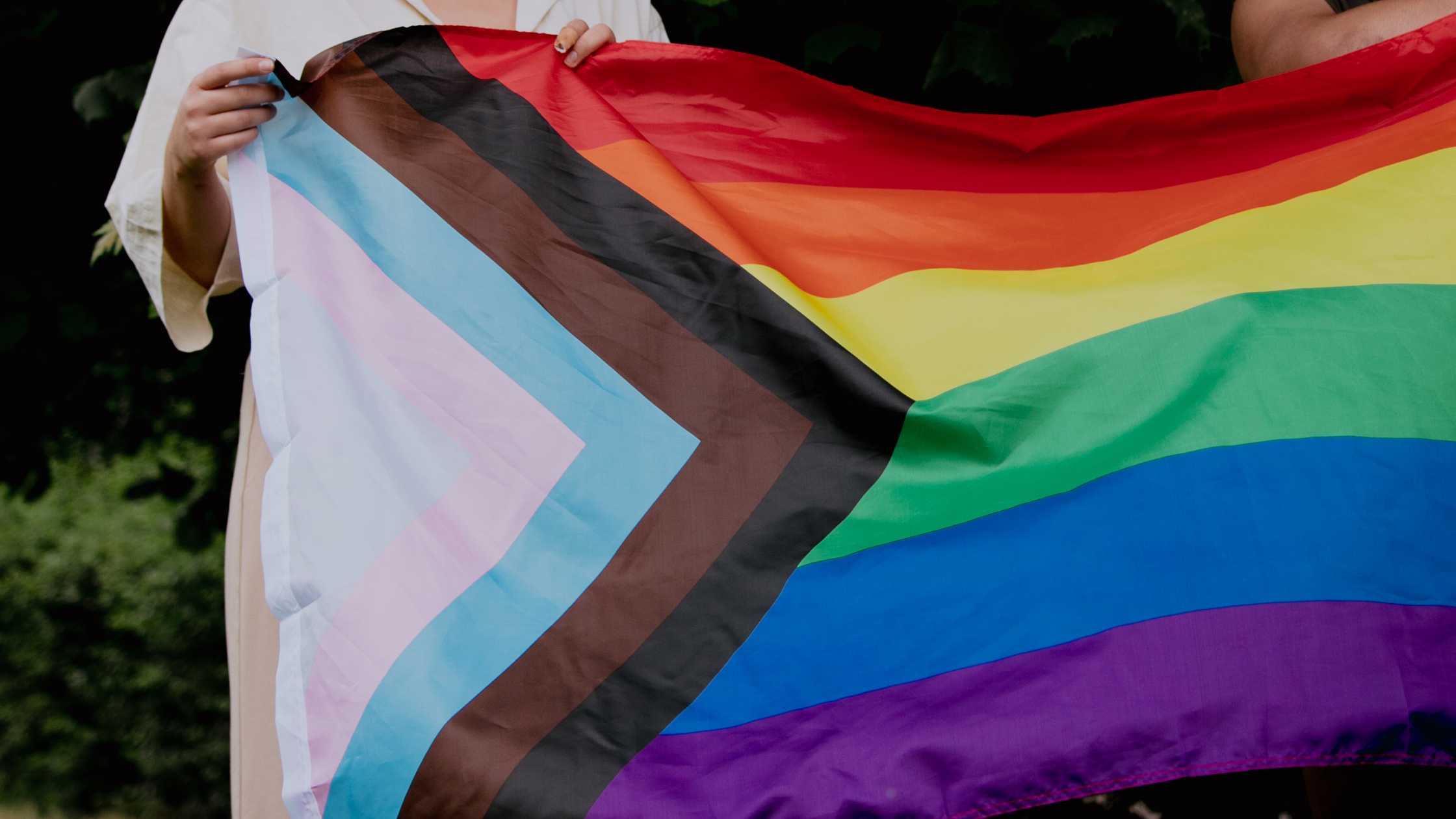 People Holding a Progress LGBTQ+ Pride Flag
