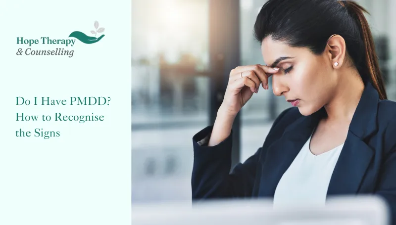 hope therapy and counselling branding with title text next to an image of a business woman sat holding the bridge of her nose with her eyes closed wondering if what she is experiencing is PMDD symptoms and how to recognise them