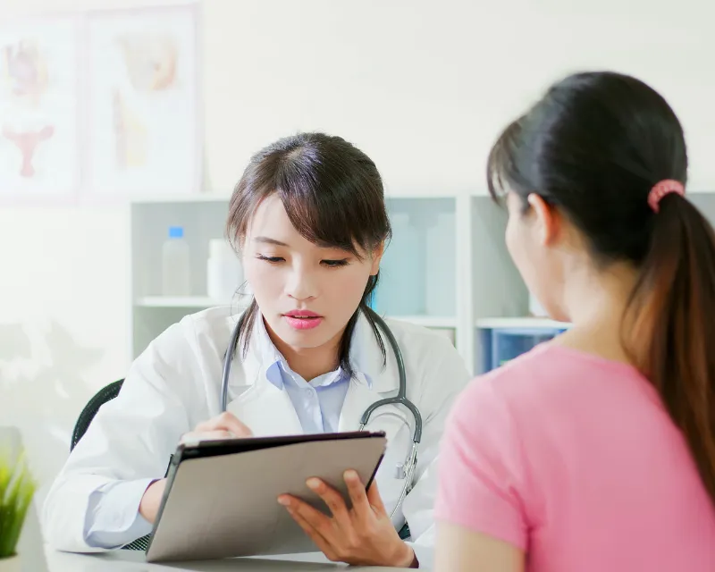 a woman in a doctors surgery with a doctor explaining the symptoms and treatment for pmdd